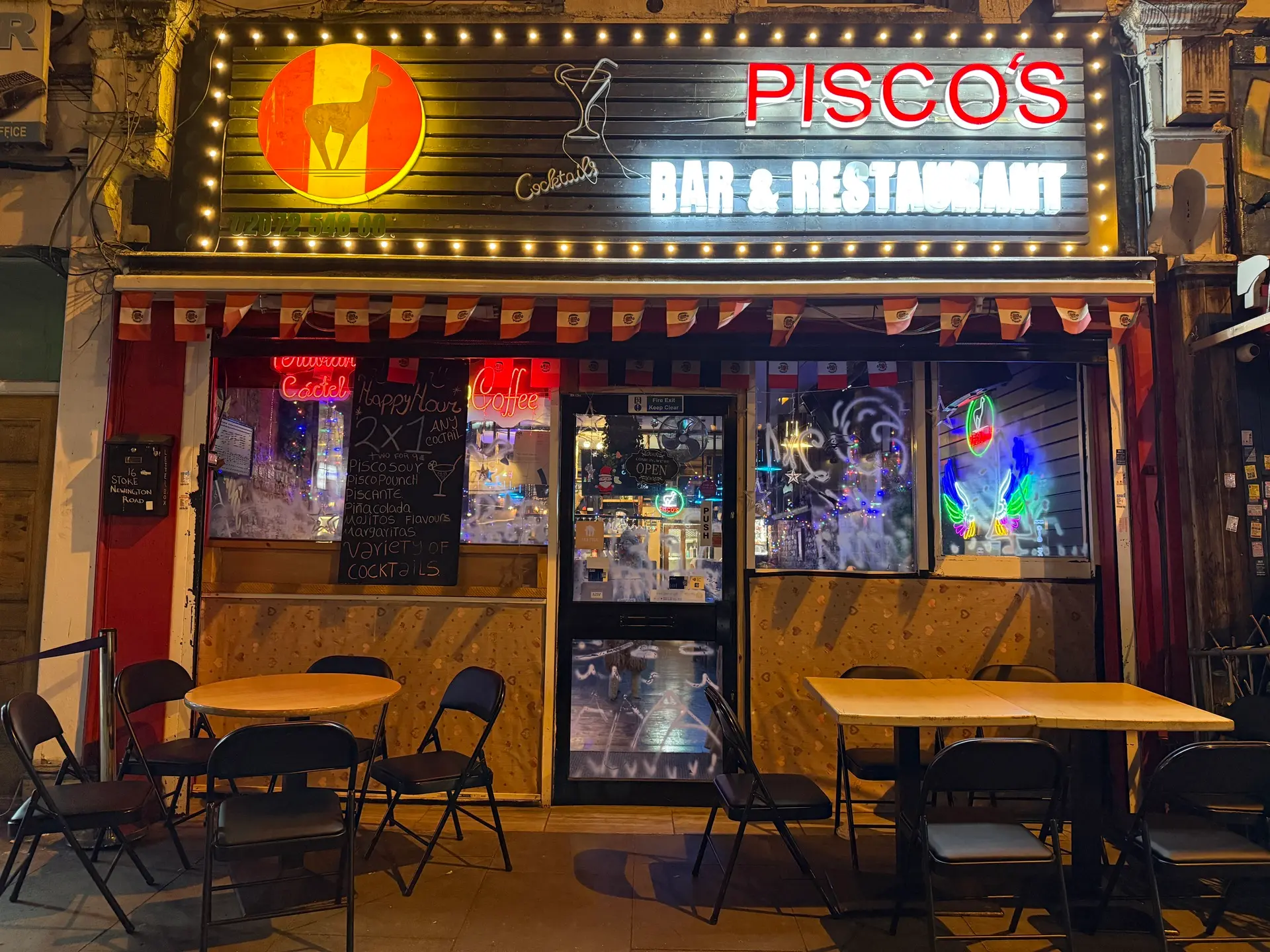 The lit Pisco's shopfront on Stoke Newington Road at night